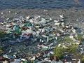 Brzeg rzeki zasłany plastikowymi butelkami i innymi śmieciami w wodzie. Smutny widok zanieczyszczenia.