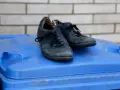 Stare, czarne buty leżą na niebieskim koszu na śmieci. Czas pomyśleć, gdzie wyrzucić buty, gdy już się zużyją.