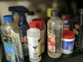 Na półce stoją różne butelki z płynami. Jedna z nich, z etykietą "Car Wash", sugeruje, gdzie wylać rozpuszczalnik, jeśli jest to konieczne.