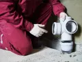 Instalator w czerwonym kombinezonie montuje białe rury kanalizacyjne. To część systemu odprowadzającego popłuczyny ze zmiękczacza wody.