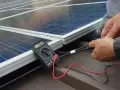 Instalator sprawdza napięcie paneli fotowoltaicznych. Dofinansowanie fotowoltaika dla firm ułatwia inwestycje w zieloną energię.