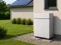 Nowoczesny magazyn energii do fotowoltaiki 10 kW stoi obok domu z panelami słonecznymi na dachu.