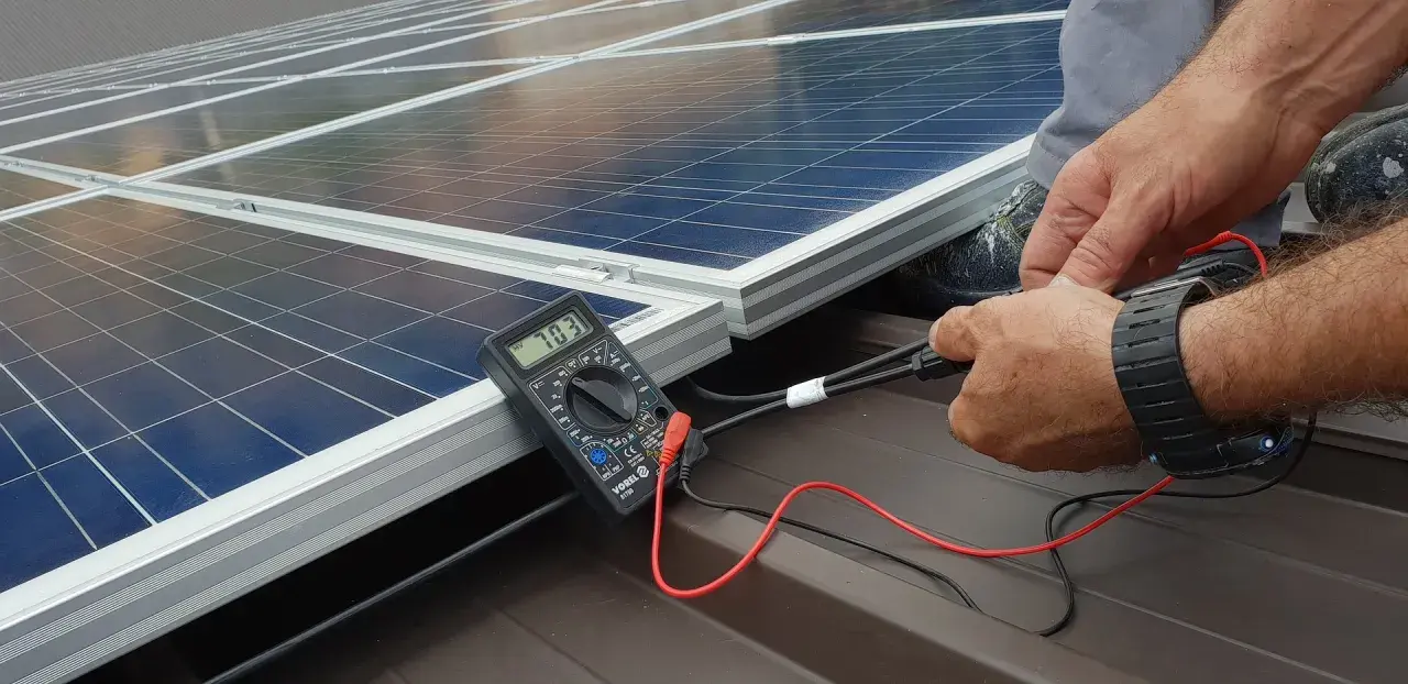 Instalator sprawdza napięcie paneli fotowoltaicznych. Dofinansowanie fotowoltaika dla firm ułatwia inwestycje w zieloną energię.