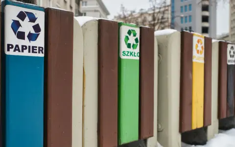 Segregacja odpadów w firmie: pojemniki na papier, szkło, plastik i inne. Zimowy krajobraz miejski.