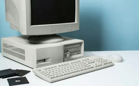 Stary komputer stacjonarny z monitorem CRT, klawiaturą, myszką i kilkoma dyskietkami.