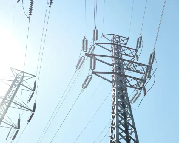 Wysokie słupy energetyczne z przewodami, przypominające o potrzebie oszczędzania i rozsądnym zarządzaniu abonamentem za prąd.