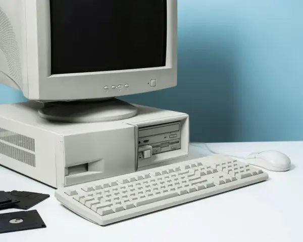 Stary komputer stacjonarny z monitorem CRT, klawiaturą, myszką i kilkoma dyskietkami.