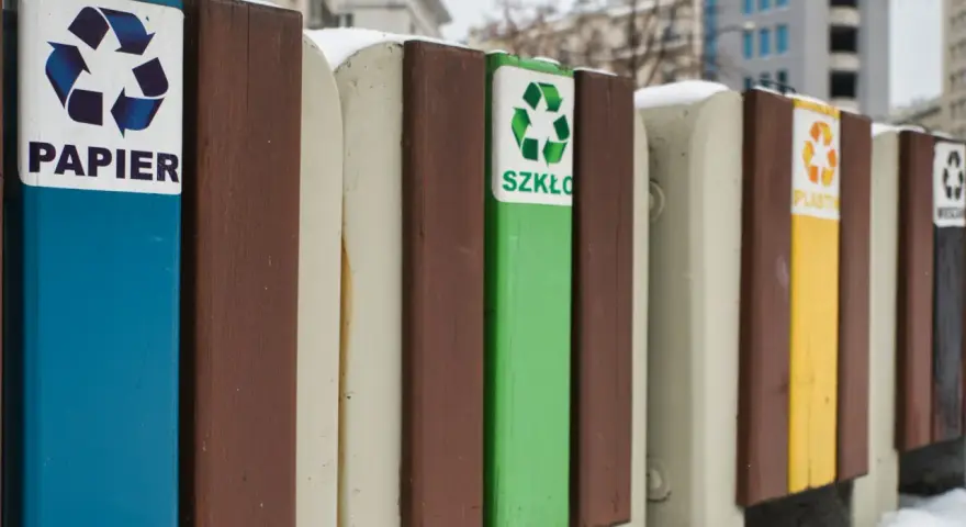 Segregacja odpadów w firmie: pojemniki na papier, szkło, plastik i inne. Zimowy krajobraz miejski.