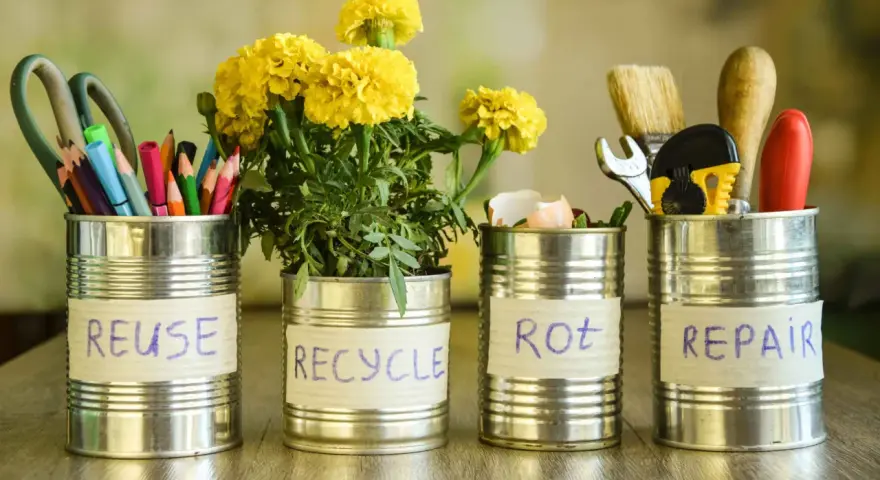 Cztery puszki po konserwach z napisami: REUSE, RECYCLE, ROT, REPAIR. W pierwszej nożyczki i kredki, w drugiej kwiaty, w trzeciej skorupki jajek, w czwartej narzędzia. Jak zrobić zgniatarkę do puszek?