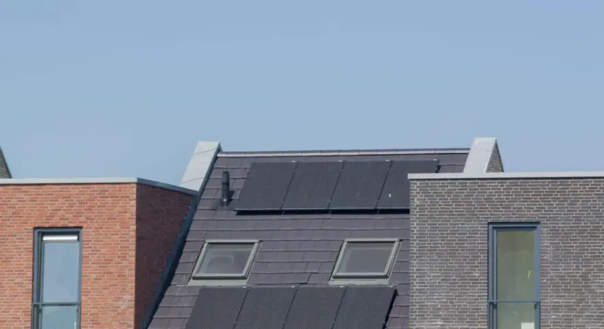 Nowoczesne dachy z panelami fotowoltaicznymi, które zapewniają zieloną energię. Domy z cegły i dachówką, z oknami dachowymi.