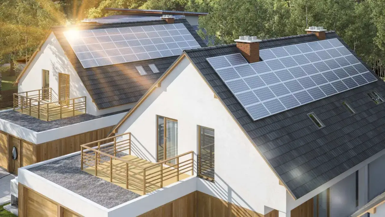 Domy z panelami fotowoltaicznymi na dachach, zapewniającymi sprawność i czystą energię. Słońce odbija się od paneli.